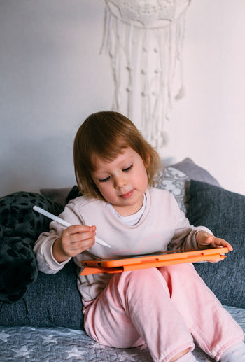 Child using technology. toddler at home with a tablet and a pen stylus and draws