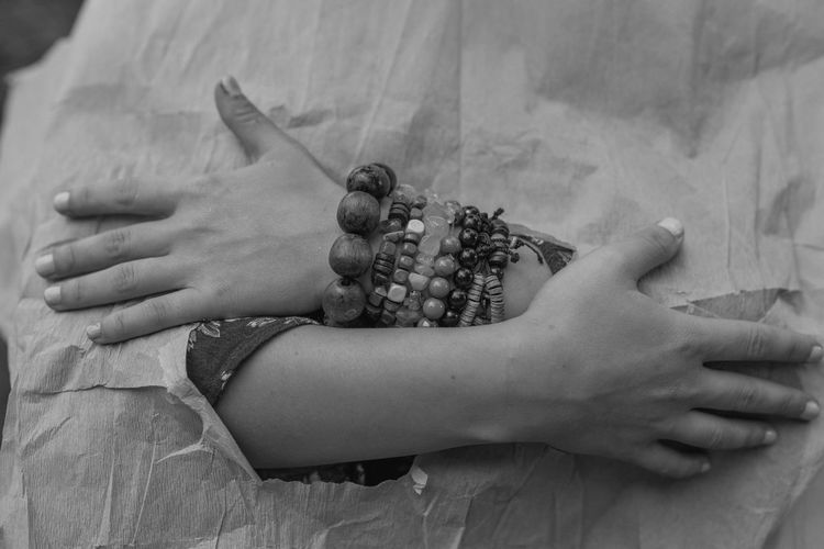 Cropped hands of woman with bracelets hugging self