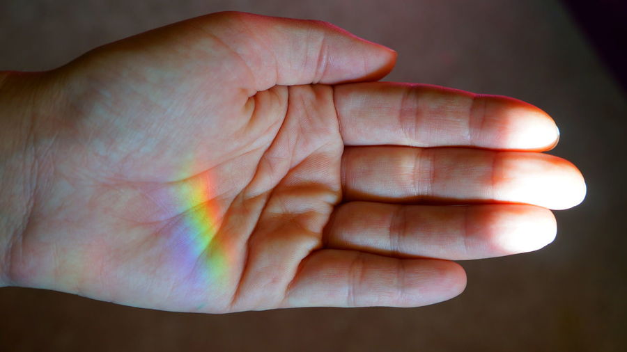 Close-up of rainbow reflecting on hand