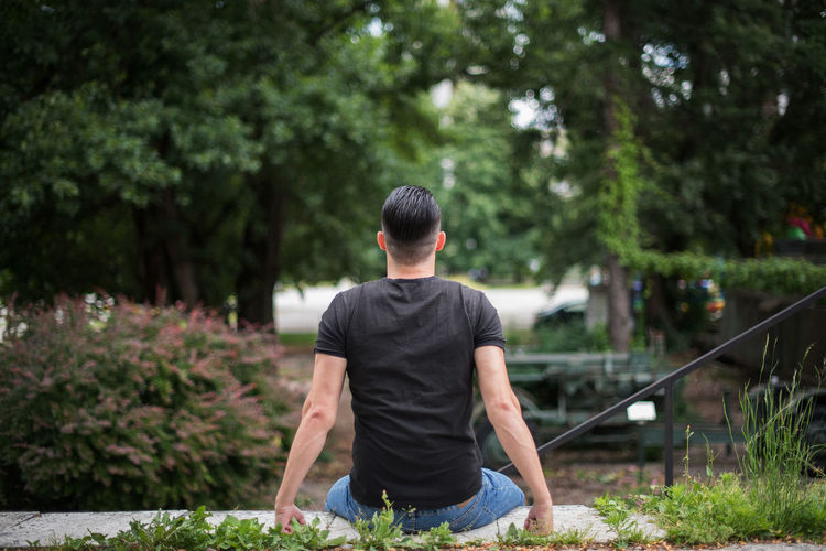 Rear view of man sitting in yard