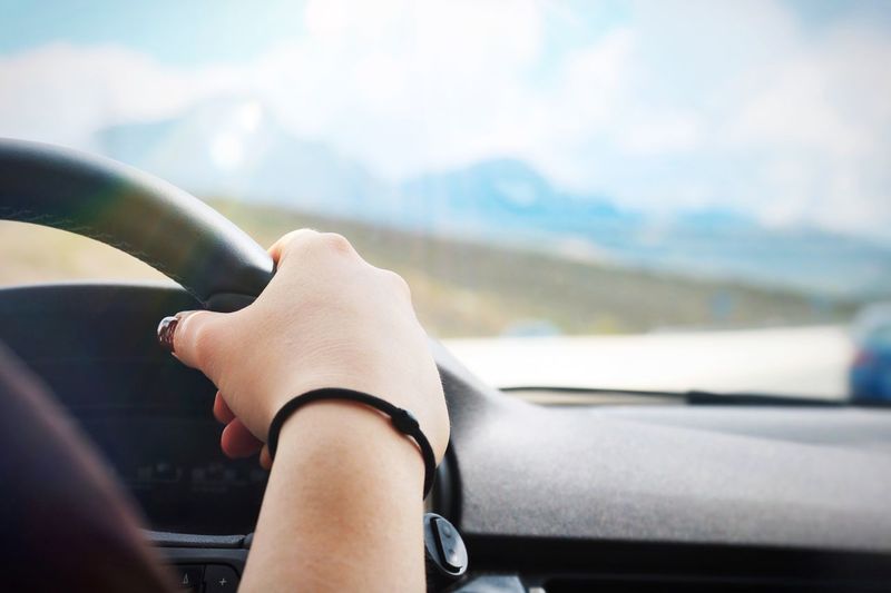 Cropped hand of woman holding steering wheel in car