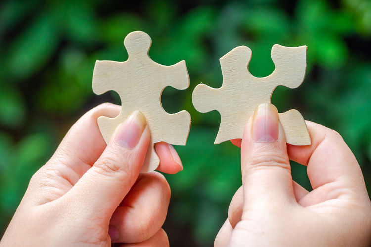 Close-up of hand holding wooden jigsaw pieces
