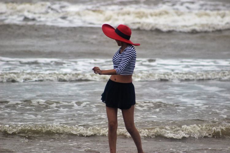 Woman looking at sea waves while walking on shore