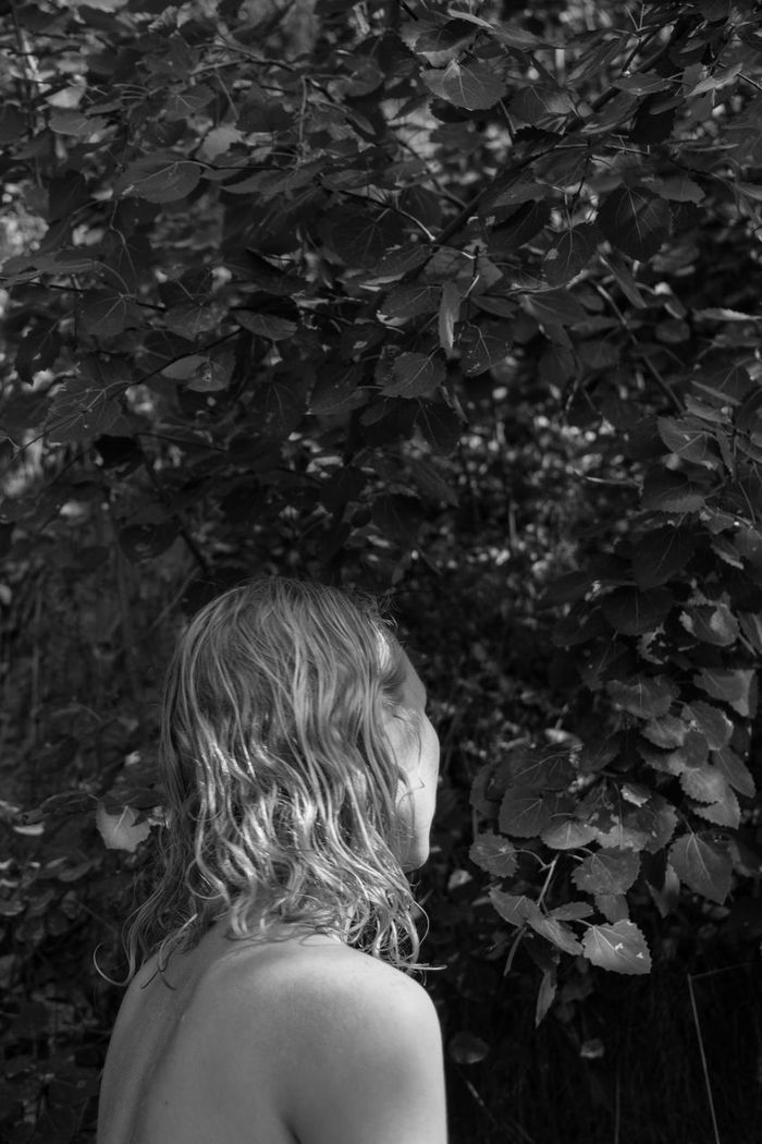 REAR VIEW OF GIRL STANDING BY PLANTS