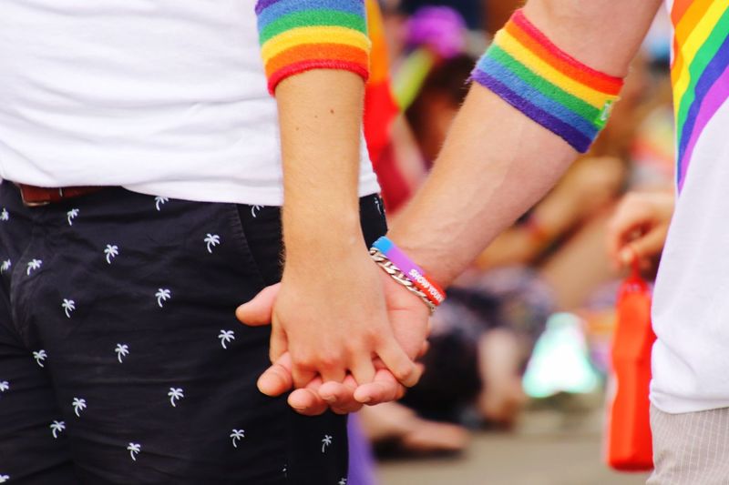 Midsection of gay men holding hands in city