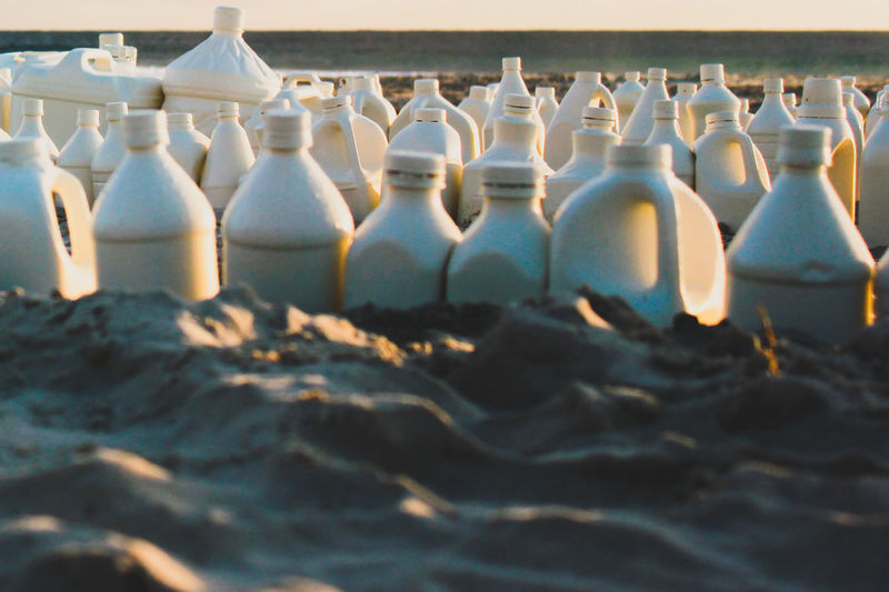 Close-up of bottles on sand at beach during sunset
