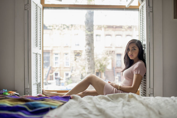 Young woman sitting on a windowsill