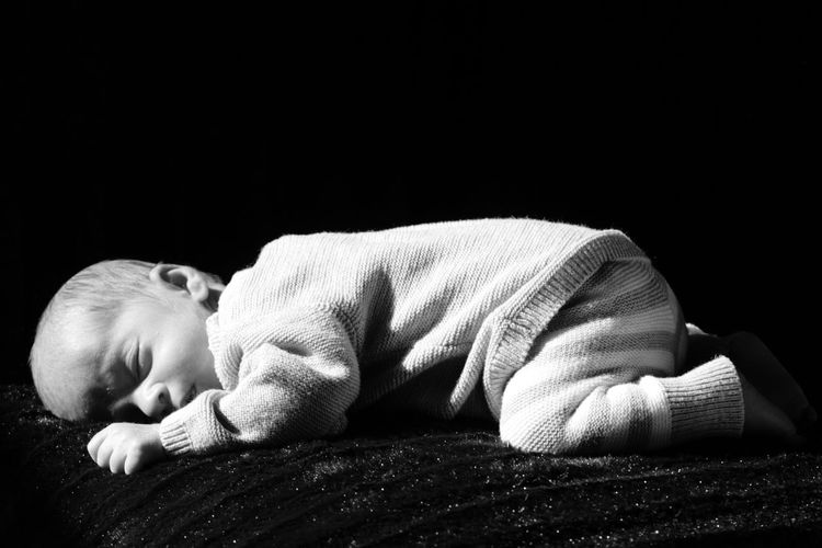 View of baby sleeping on bed against black background