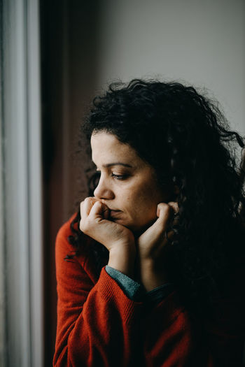 Depressed woman sitting by window