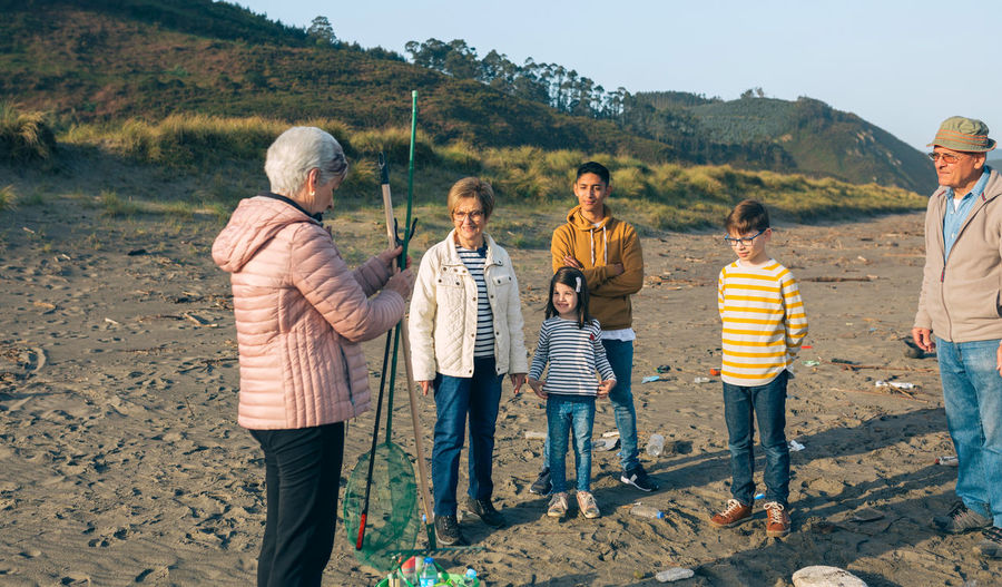 Family looking at senior woman while holding fishing net at beach