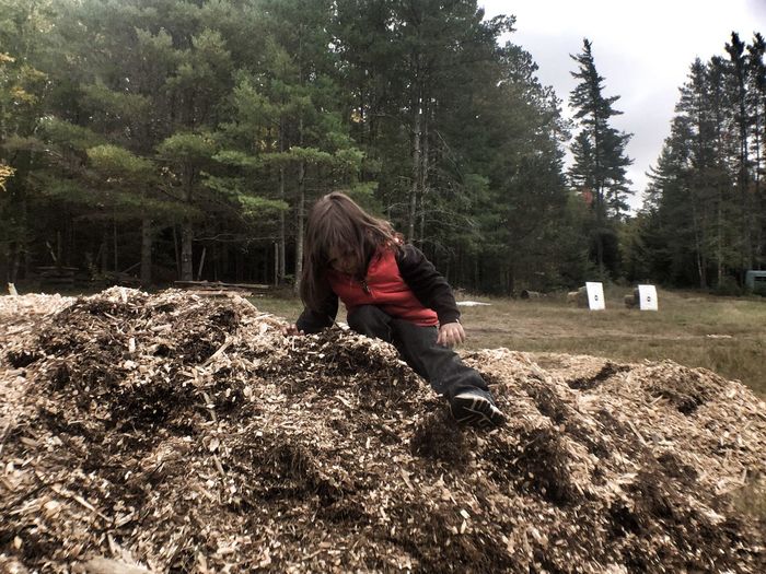 Girl sitting on heap of wood chips