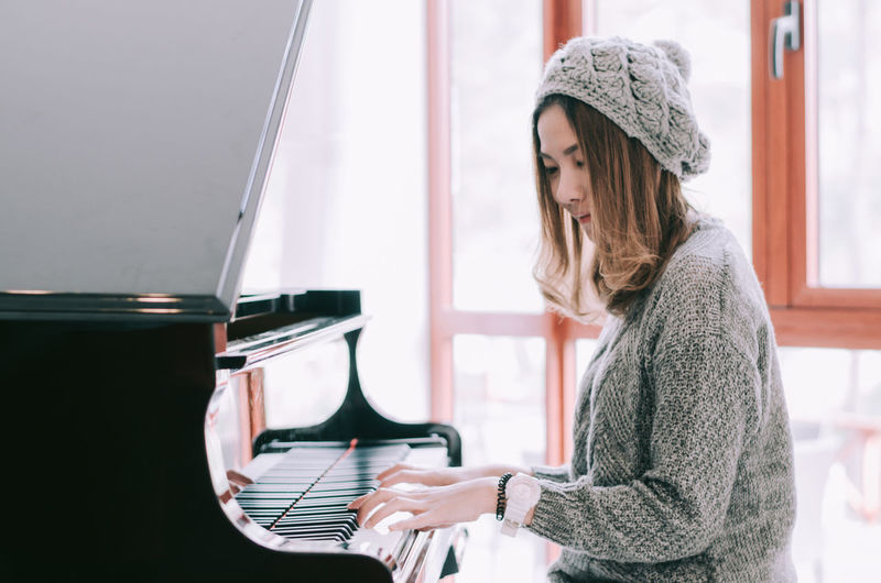 Young woman wearing hat while standing at home