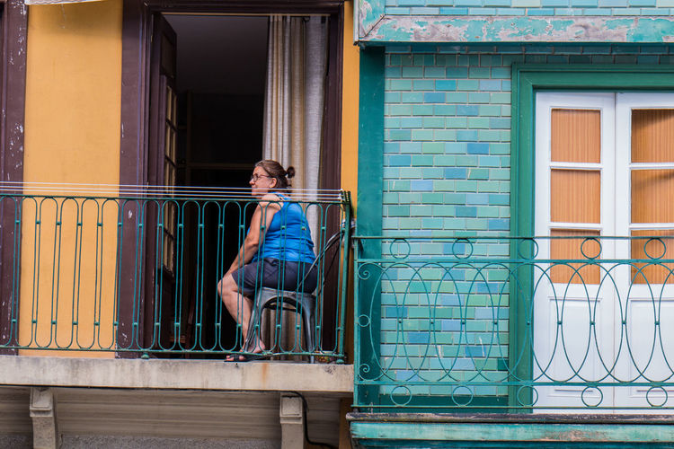 Side view of woman sitting on table by railing