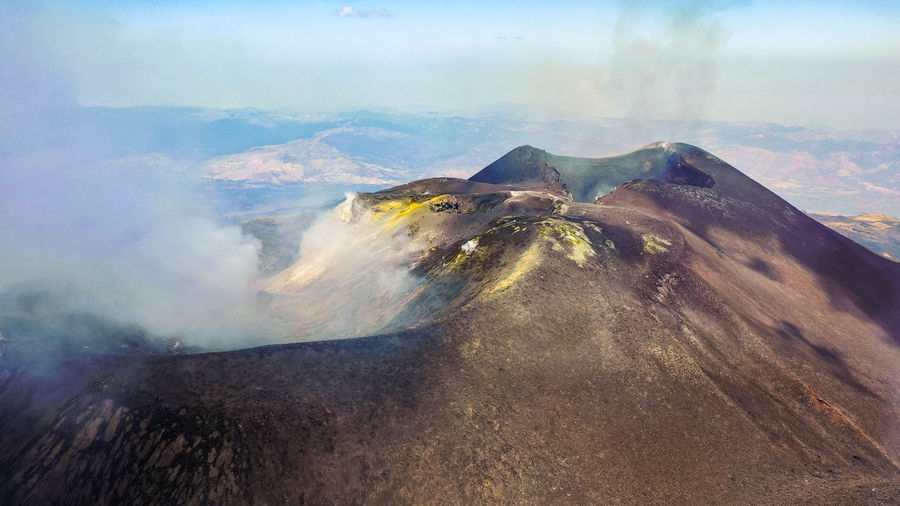 Crater etna top view from above in a panoramic aerial photo with sulphure and smoke at degassation