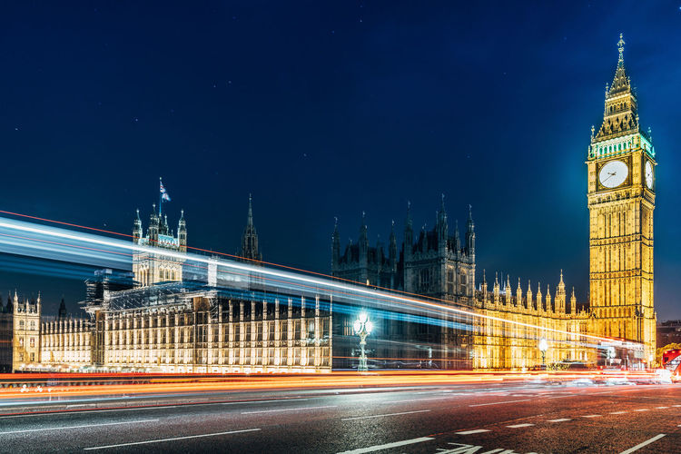 Light trails on road against houses of parliament and big ben