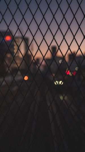 Defocused image of city seen through chainlink fence