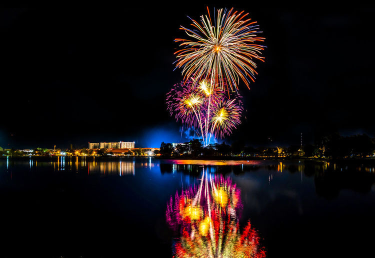 Firework display over lake at night