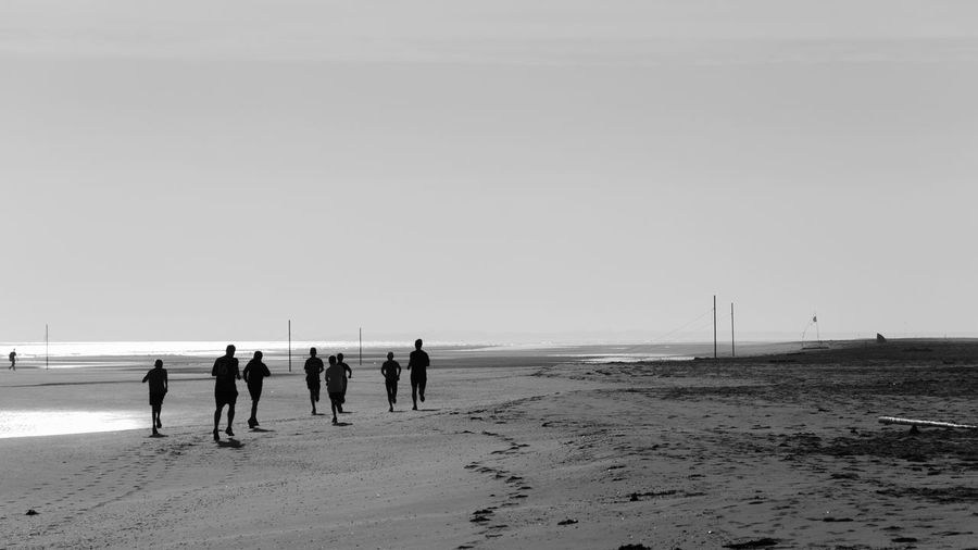 People walking on beach against clear sky
