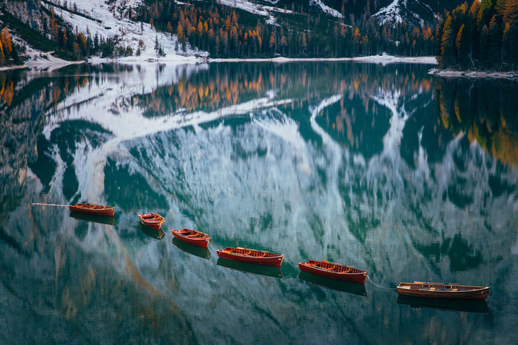 Boats in lake against snowcapped mountains