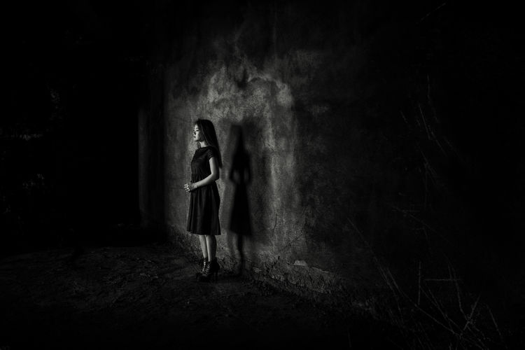 Digital composite image of woman standing in dark room