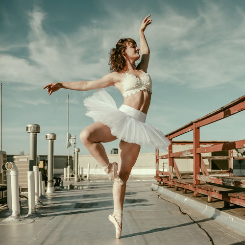 Full length of woman with arms raised against sky