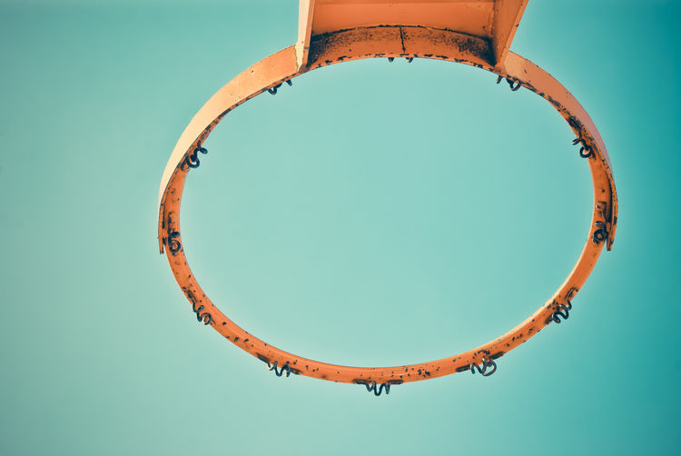 Directly below shot of old basket ball hoop against blue sky