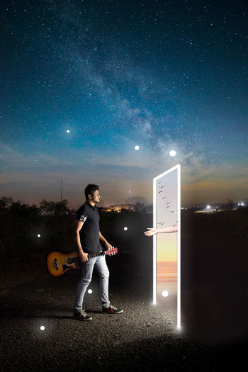 Full length of man standing against illuminated star field at night