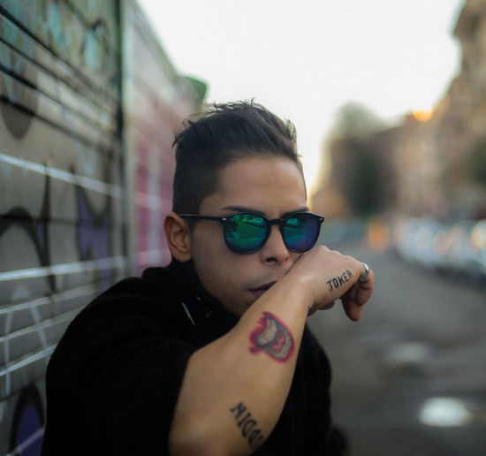 Portrait of man with tattooed hand wearing sunglasses in city
