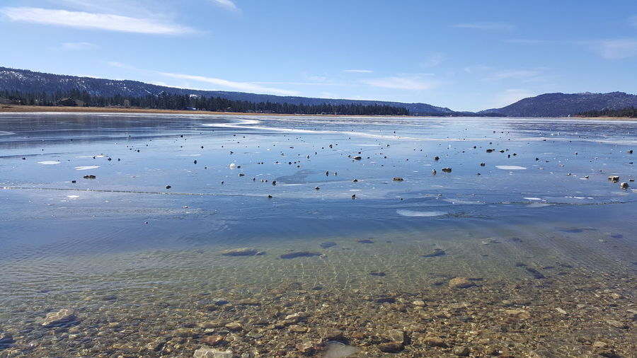 Rocks in frozen big bear lake against sky
