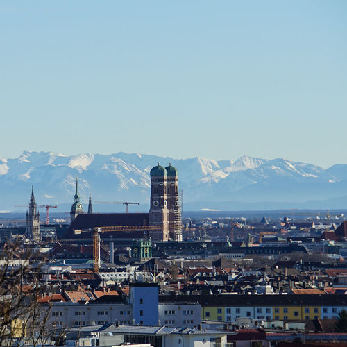 Panoramic view of munich skyline with frauenkirche and other cathedrals in front of the alps at noon