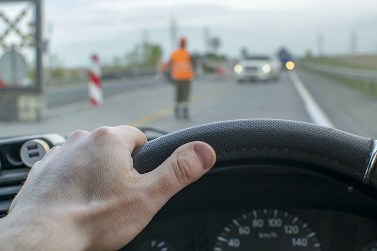 Driver hand is on the steering wheel, which stands and passes oncoming cars