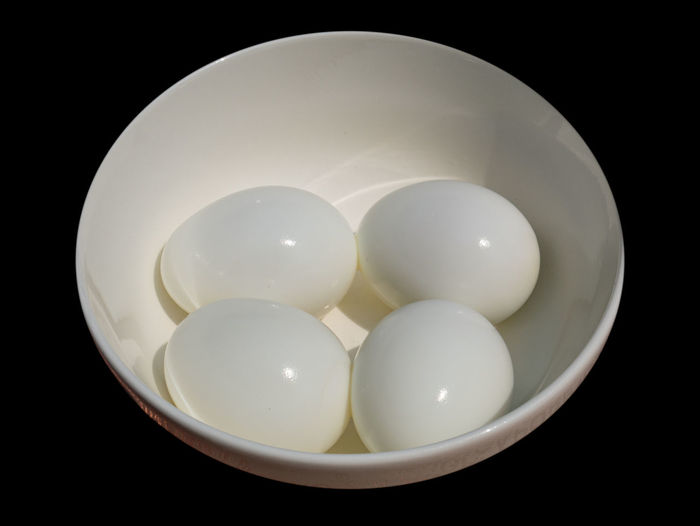 Photo of four boiled eggs in a white bowl.