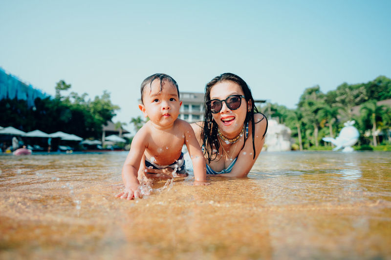 Portrait of mother with baby lying down in water outdoors