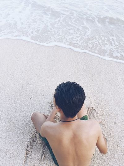 Rear view of shirtless boy at beach