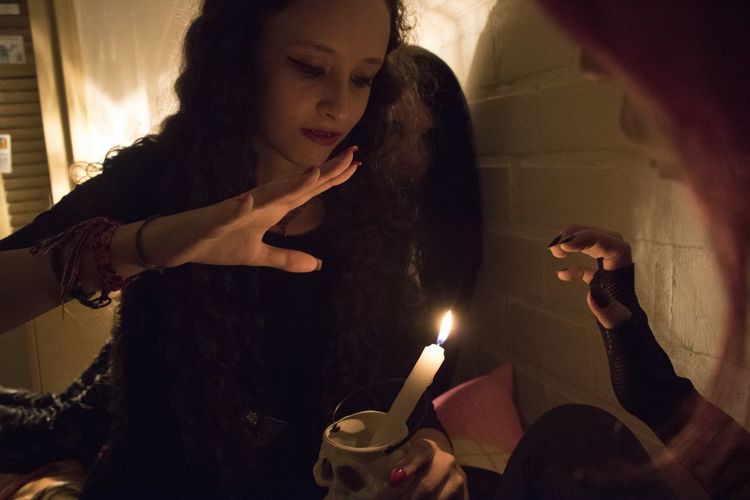 Friends looking at illuminated candle during wiccan ceremony