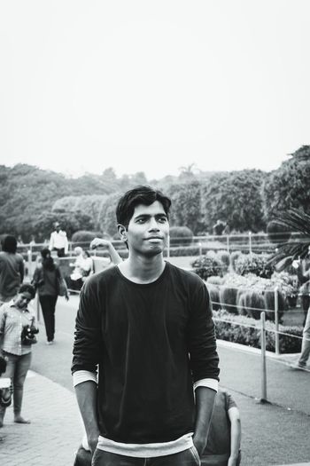 Young man looking away while standing in public park