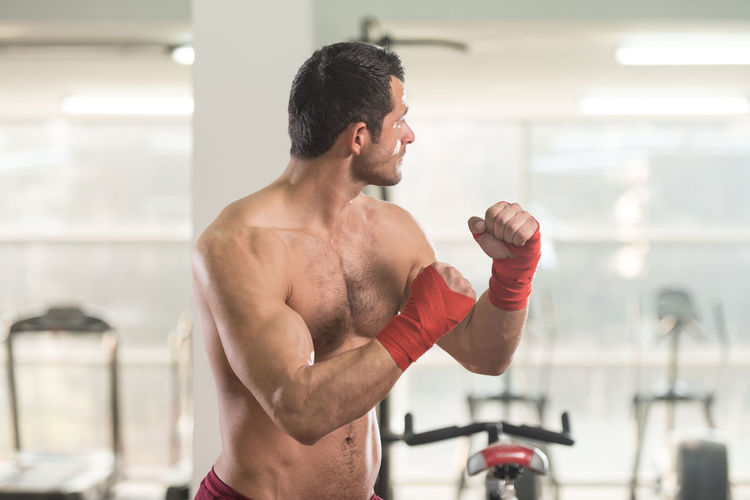 Muscular shirtless man standing in gym