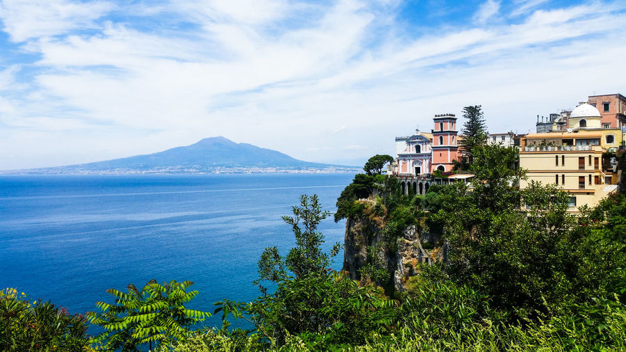 Scenic view of sea by buildings against sky
