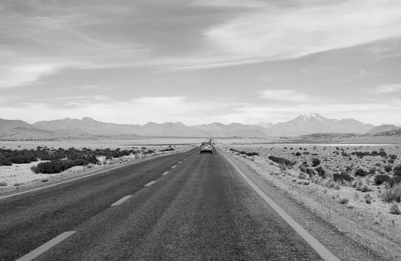 Monochrome of a car driving on the desert road of northern chile, south america