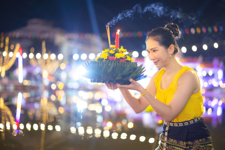 Side view of young woman holding sparkler at night