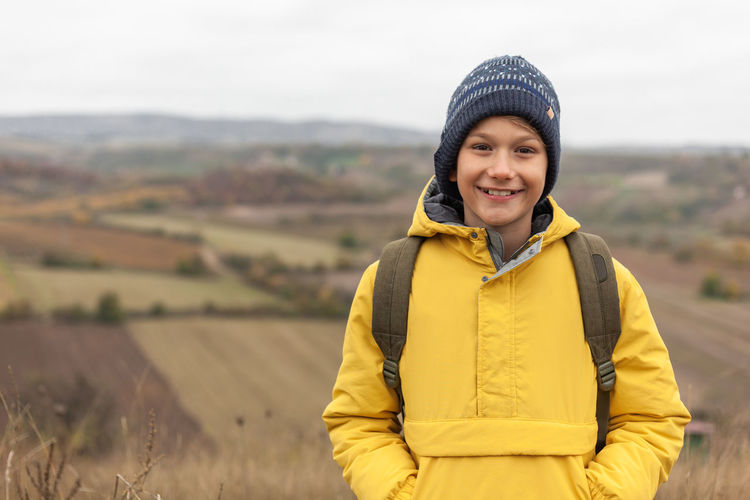 Portrait of smiling young woman standing against yellow during winter