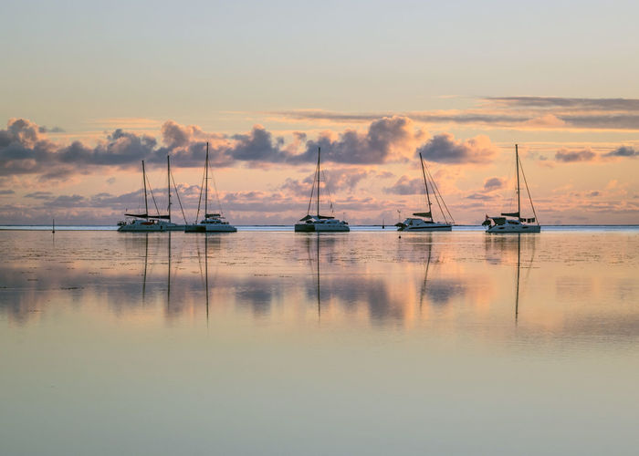 Sailboats in sea at sunset