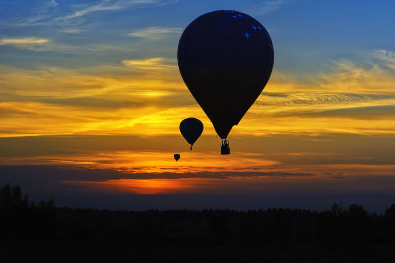 Silhouette hot air balloon against orange sky