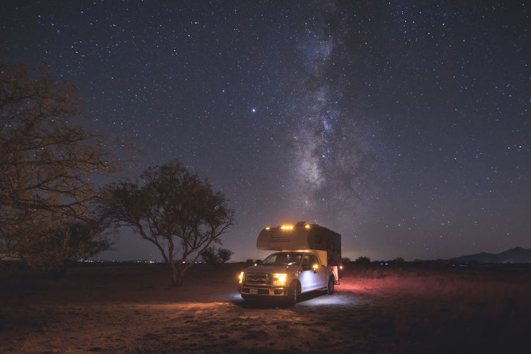 A small pickup rv is on a camping spot under the milky way