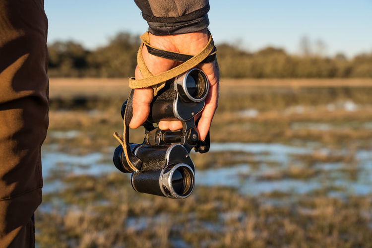 Cropped unrecognizable man looking through an old binoculars the fauna of a lagoon in spain