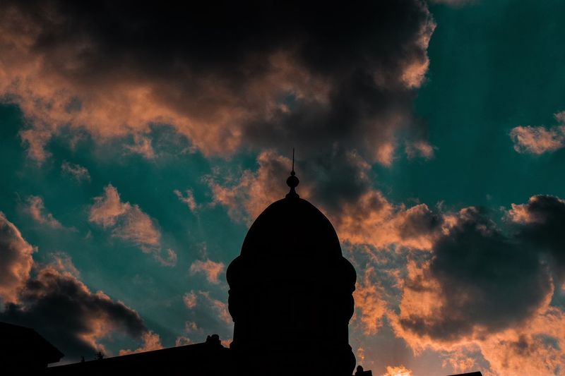 Low angle view of silhouette building against cloudy sky during sunset