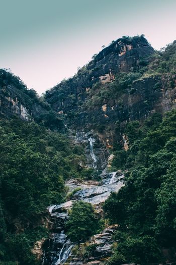 Scenic view of waterfall in forest against clear sky