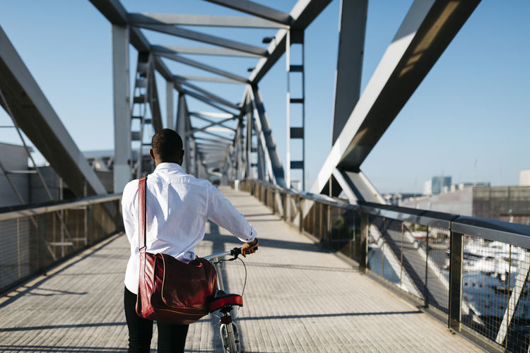 Man pushing bicycle on a bridge