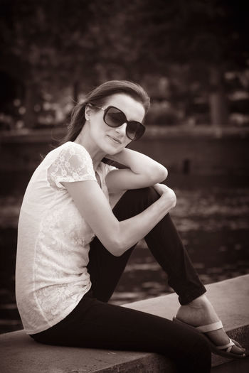 Midsection of woman with sunglasses sitting outdoors