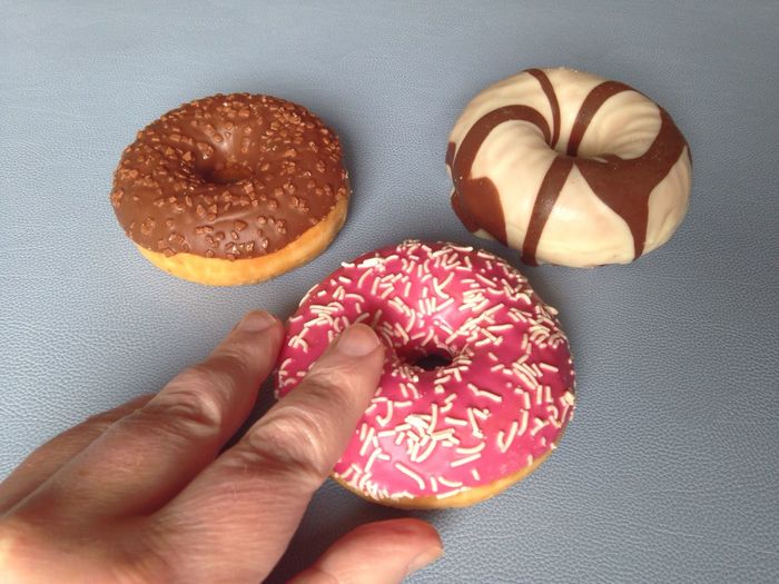 Close-up of cropped hand touching donut on table